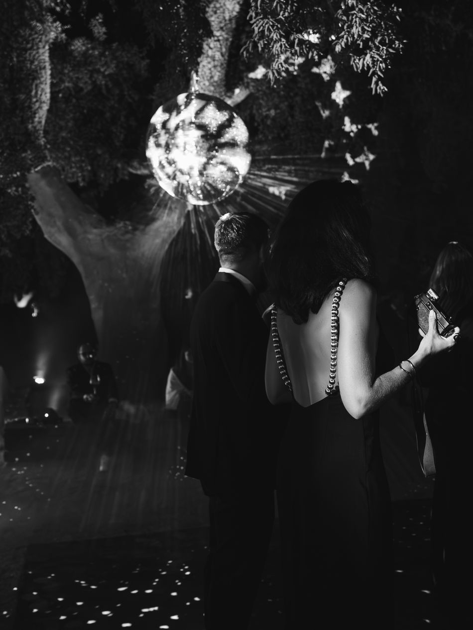 A mirrorball turning above the dance floor beneath the trees, photographed in black and white